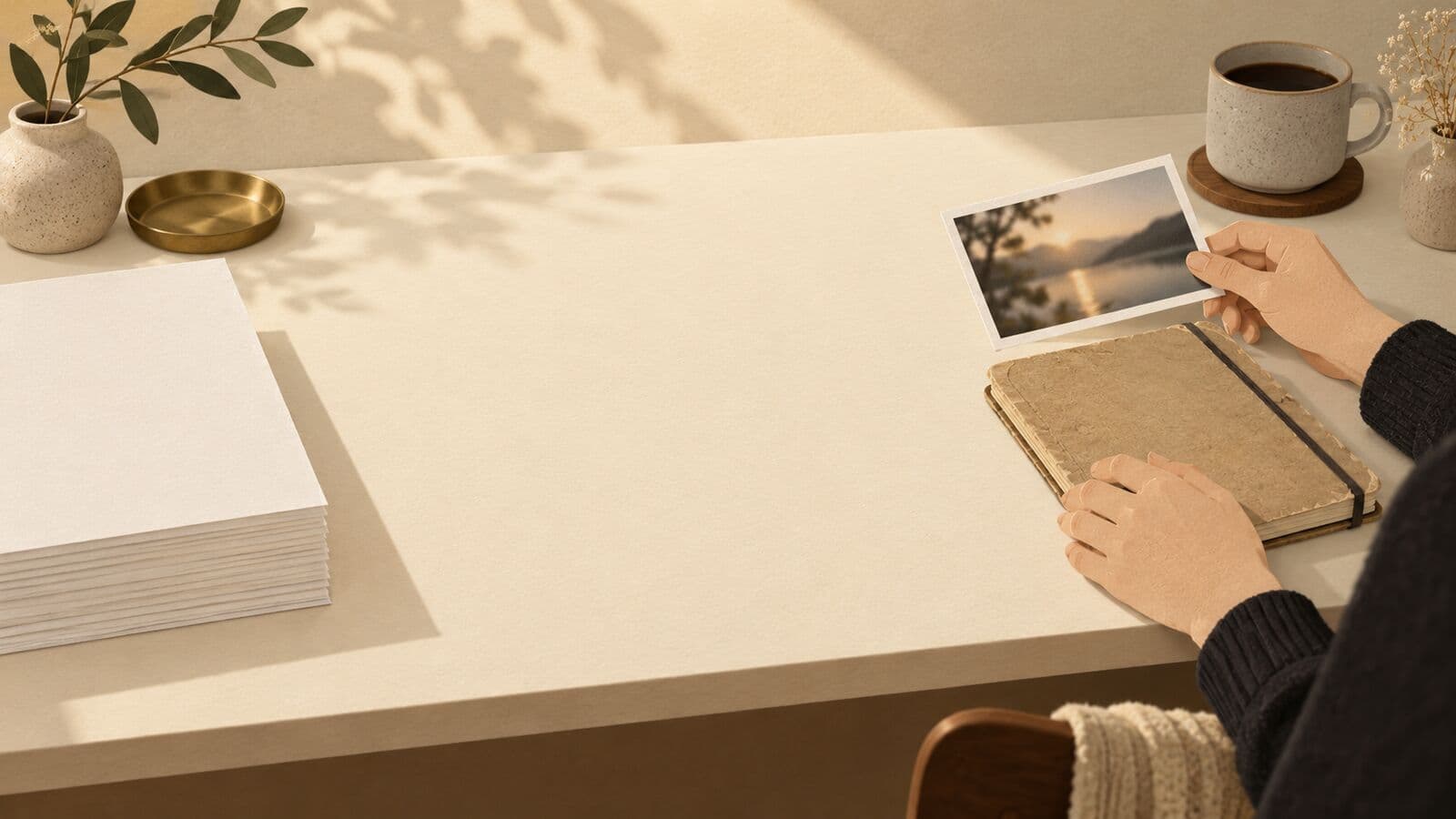 Paper cut-out of identical blank printouts at one end of a desk and a photograph and notebook at the other.